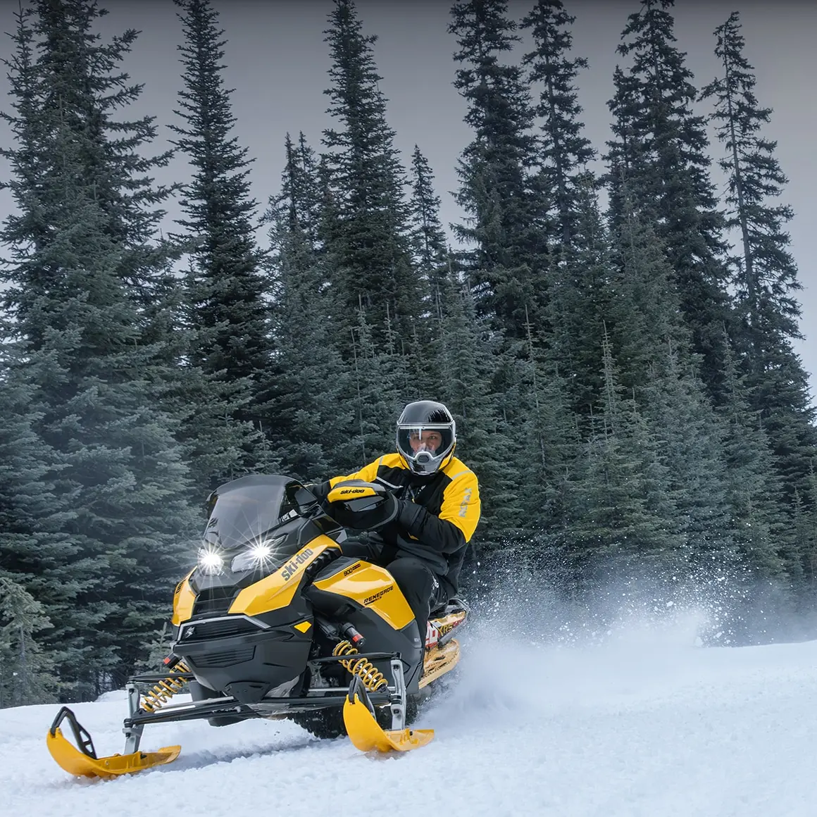 Gul Ski-Doo-snöskoter på en snöig skogsled